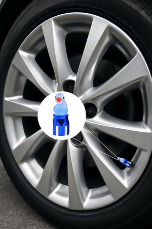 Blue duck valve stem cap with safety tether shown on a silver car wheel; cute decorative tire accessory.
