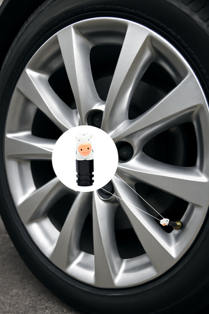 Cow-shaped valve stem cap installed on a car wheel, featuring a cute white cow design for automotive decoration.