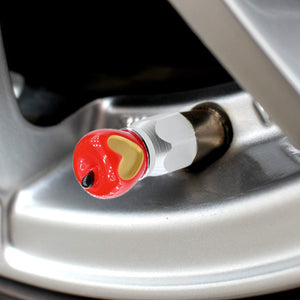 Xalvoria red Apple Core valve stem cap being hand-installed onto a tire valve stem showing easy twist-on application.