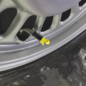 Yellow duck valve stem cap attached to a car rim, highlighting decorative and protective design.