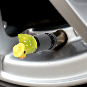 Close-up view of a yellow duck valve stem cap installed on a car wheel.