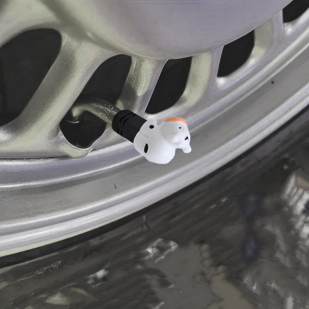 Cow-shaped valve stem cap installed on a car wheel in a real-scene setting, showing the white cow design with black details.
