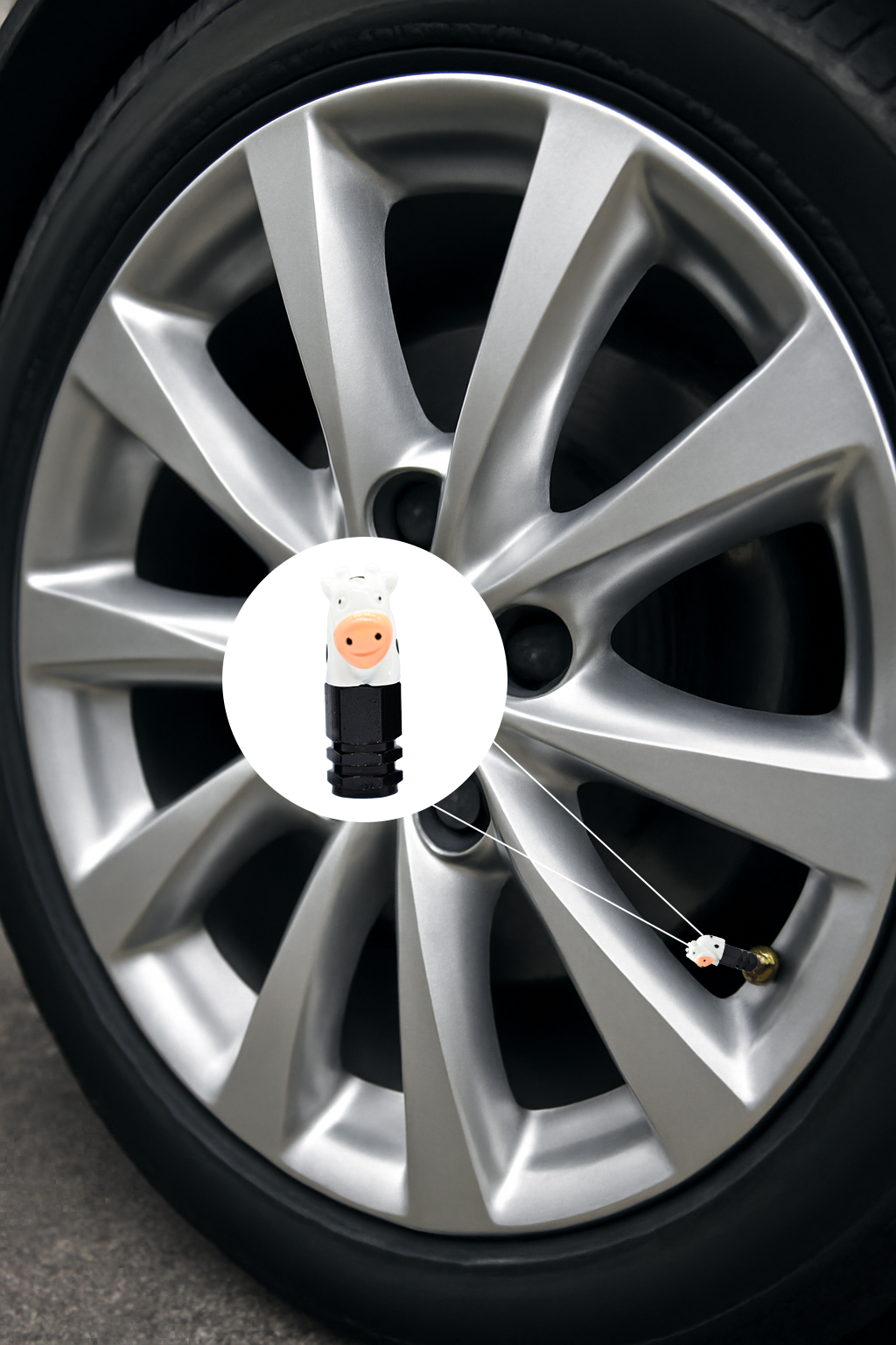 Cow-shaped valve stem cap installed on a car wheel, featuring a cute white cow design for automotive decoration.