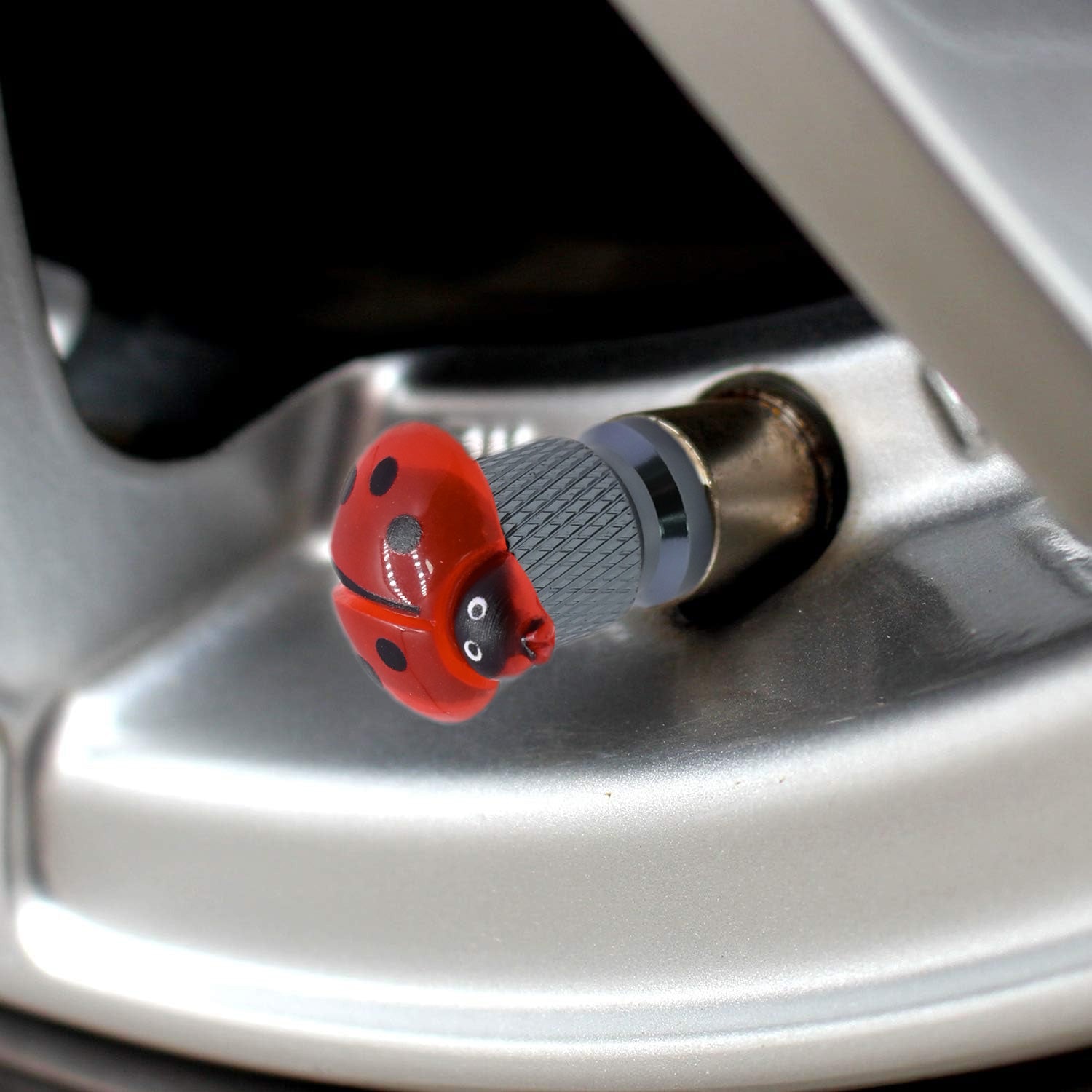 Close-up view of the ladybug valve stem cap installed on a car tire valve – Xalvoria