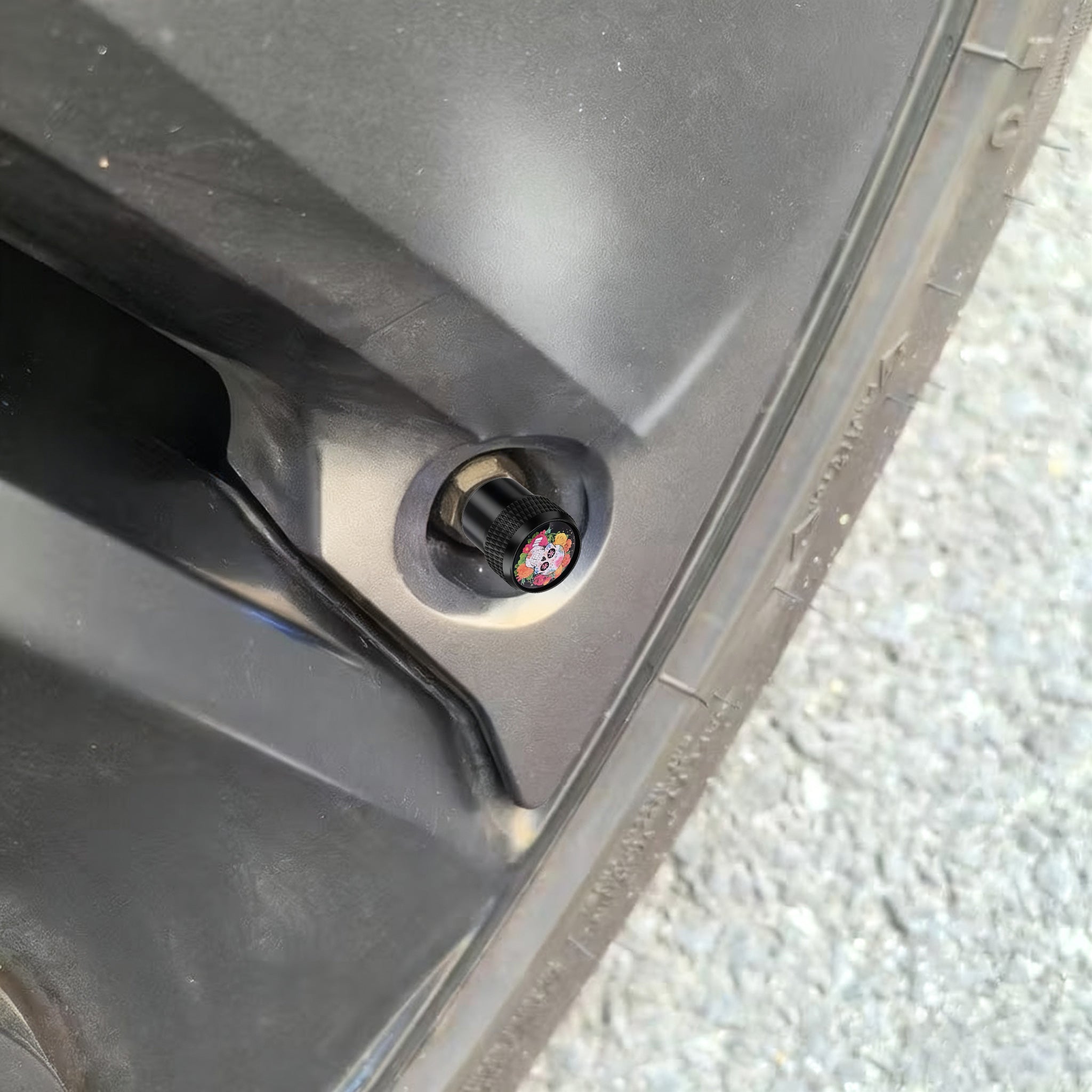 Sugar skull valve stem cap installed on a car wheel, showing the real-life fit and decorative appearance on the tire valve.
