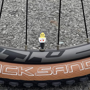 Xalvoria Black Base Yellow Eggshell Chicken valve stem cap installed on a bicycle wheel