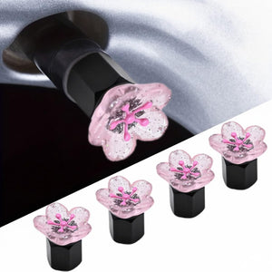 Xalvoria pink cherry blossom valve stem caps 4-pack with resin flower toppers installed on a tire valve.