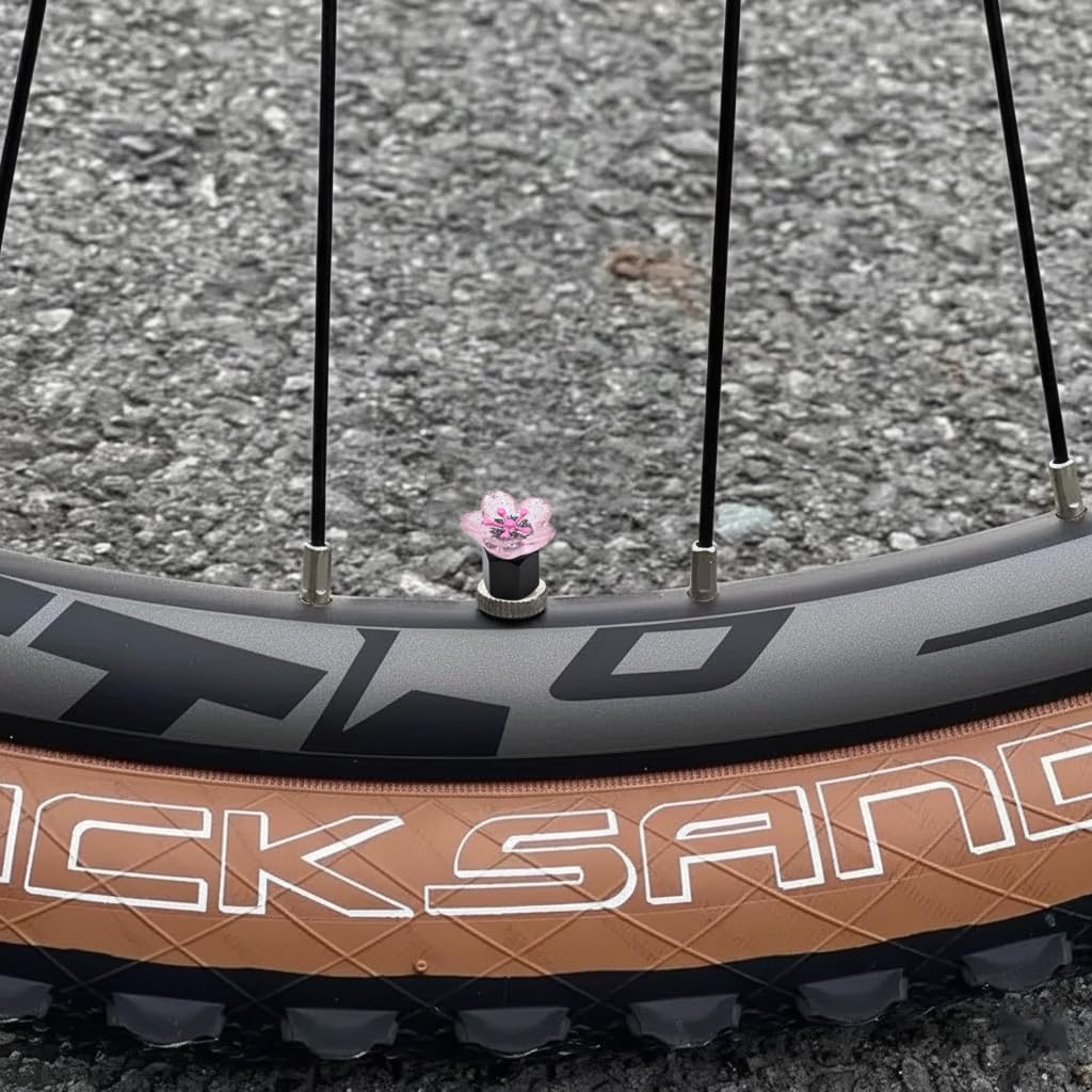 Xalvoria pink cherry blossom valve stem cap installed on a bicycle valve for decorative enhancement.