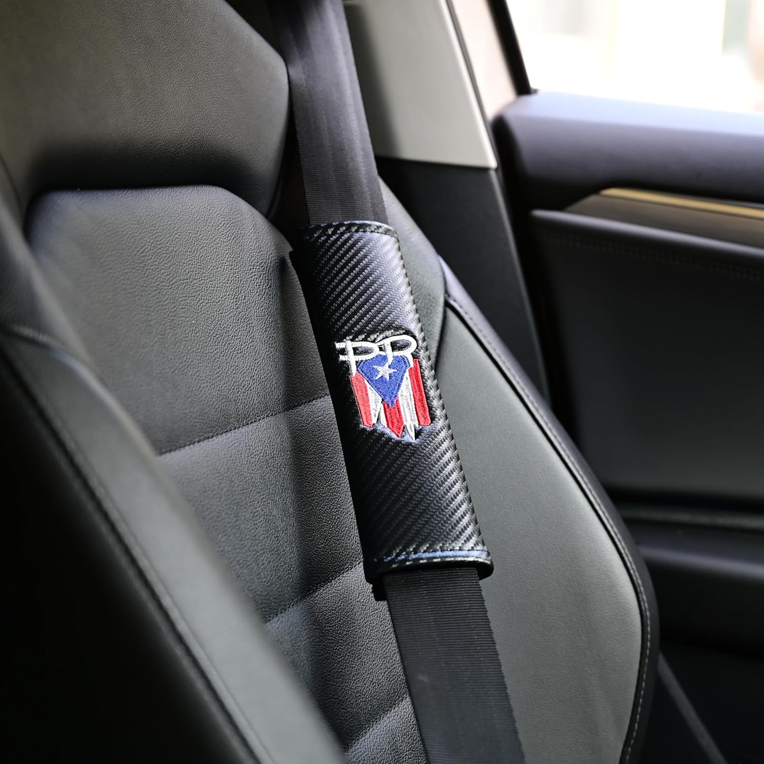 Xalvoria PR seatbelt cover installed on car seat, carbon-fiber texture with embroidered PR logo
