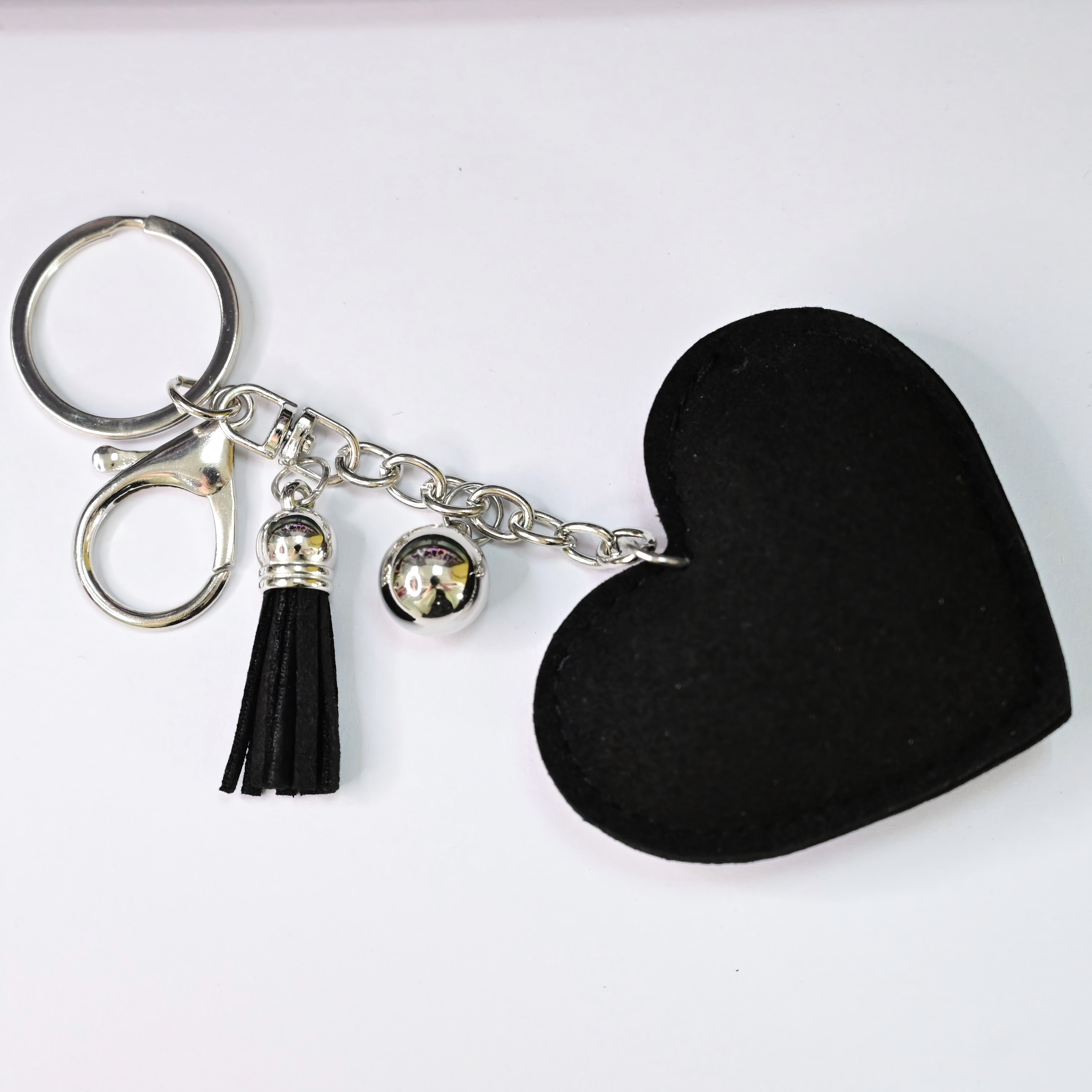 Xalvoria heart-shaped keychain back view with black faux suede finish and tassel charm