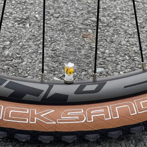 Xalvoria yellow bee valve stem cap attached to a bicycle tire valve, adding a fun and playful detail to the bike.