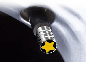 Yellow star valve stem cap installed on a car wheel, showing the chrome metal finish and decorative design on the tire valve.